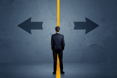 Business person choosing between two options separated by a yellow border arrow conceptの写真素材