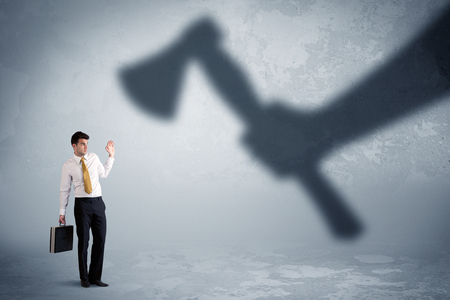 Businessman afraid of a huge shadow hand holding an axe conceptの写真素材
