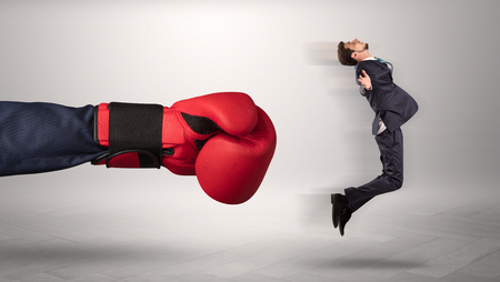 Giant hand gives a kick to a small businessmanの写真素材