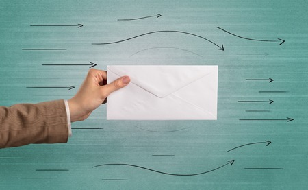 Hand holding envelope with arrows aroundの写真素材