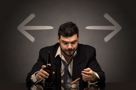Drunk man sitting at table with arrows aroundの写真素材