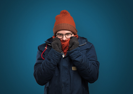 Handsome boy freezing in warm clothingの写真素材