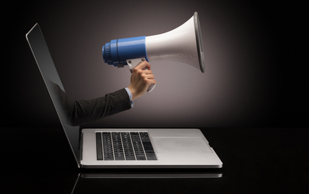 Hand with loudspeaker coming out of a laptopの写真素材