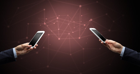 Close up of two hands holding smartphones