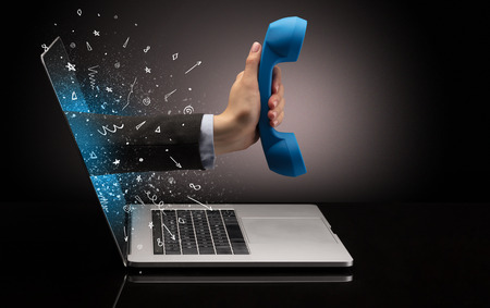 Hand with phone coming out of a laptopの写真素材