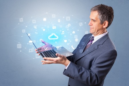 Man holding laptop with cloud based system notificationsの写真素材