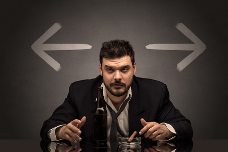 Drunk man sitting at table with arrows aroundの写真素材