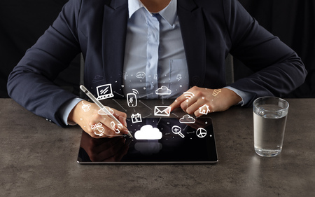 Business woman working on tablet with application symbols above