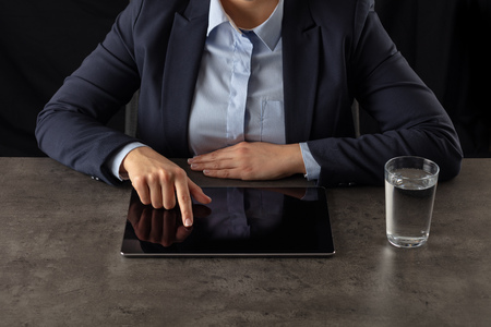 Business woman working on tablet with dark backgroundの写真素材
