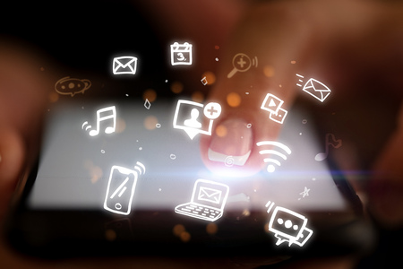 Finger touching phone with hologram app icons aboveの写真素材