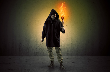 Man walking in an empty space with burning flambeauの写真素材