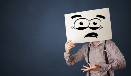 Person holding a paper with funny emoticon in front of her faceの写真素材