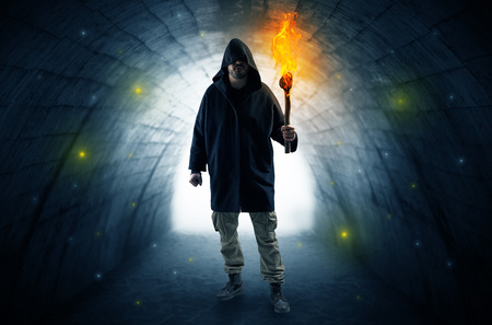 Man walking with burning flambeau in a dark tunnelの写真素材