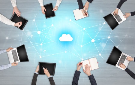 Group of people with devices in hands working on laptops and tabletsの写真素材