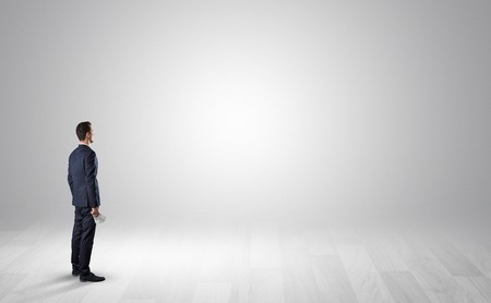 Man standing with his back in an empty room with object in his handの写真素材