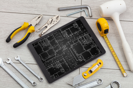 Tablet with construction tools and blueprint concept