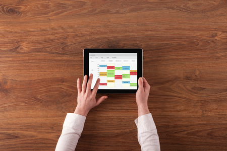 Hand holding tablet with timetable and calendar conceptの写真素材