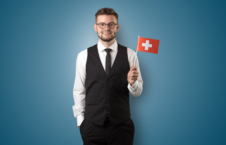 Cheerful student standing in front of wall with national flag on his handの写真素材