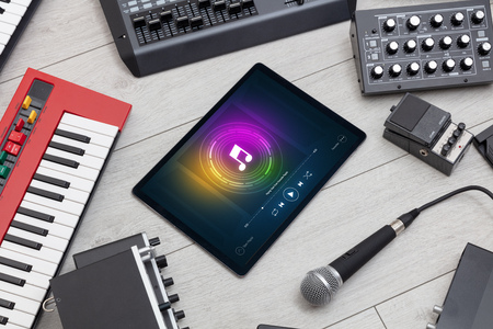 Playing song on tablet with electronic music instruments around