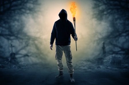 Man with burning flambeau coming from thicket and looking somethingの写真素材