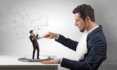 Big boss eating small businessman with knife and forkの写真素材