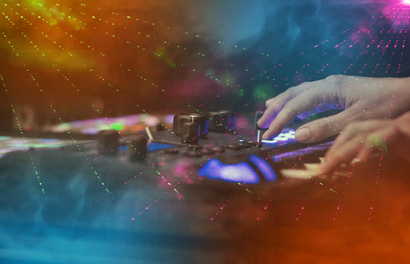 Hand mixing music on midi controller with party club colors aroundの写真素材