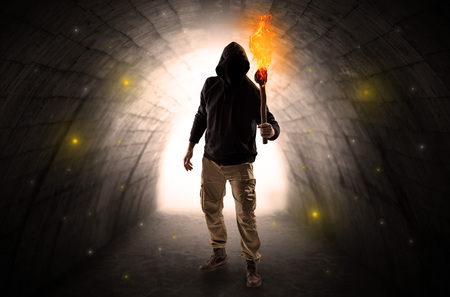 Ugly man with burning flambeau walking in a dark tunnelの写真素材