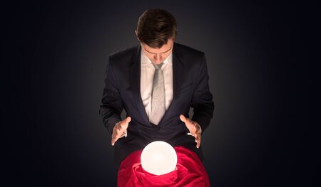 Handsome businessman with magic ball and copy space and dark backgroundの写真素材