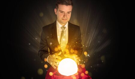 Gorgeous businessman sitting with sparkling magic ball in his lapの写真素材