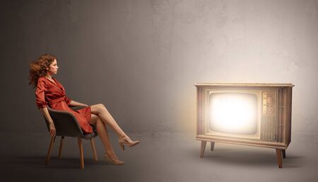 Elegant young lady watching to a vintage televisionの写真素材