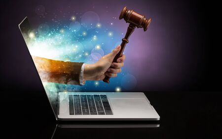 Hand with hammer coming out of a laptop with sparkling effectsの写真素材