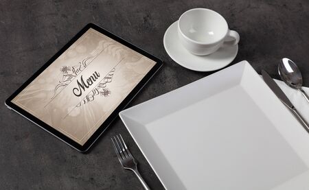 Tablet with stylish restaurant logo and laid tableの写真素材