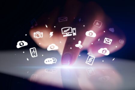 Finger touching tablet with white drawn application icons and dark backgroundの写真素材