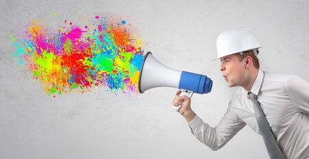 Young architect constructor yelling with megaphone with and colorful splash conceptの写真素材
