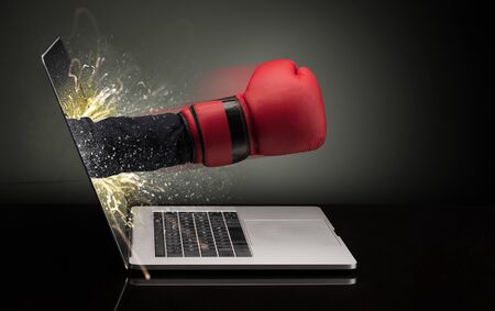 Hand with box gloves coming out of a laptop with sparkling effectsの写真素材