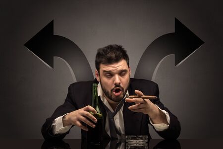 Drunk disappointed man sitting at table with arrows aroundの写真素材