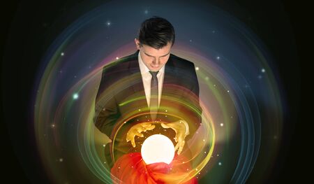 Young handsome man looking to the future of the universe in a crystal ballの写真素材