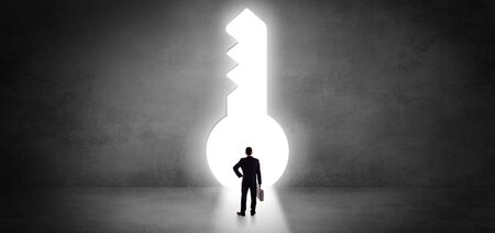 Businessman standing alone in front of a big keyholeの写真素材