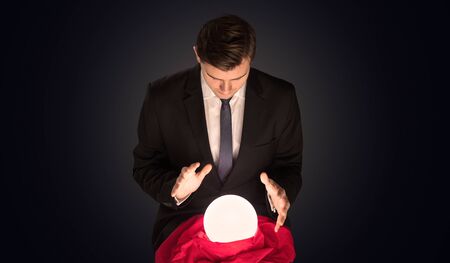 Handsome businessman with magic ball and copy space and dark backgroundの写真素材