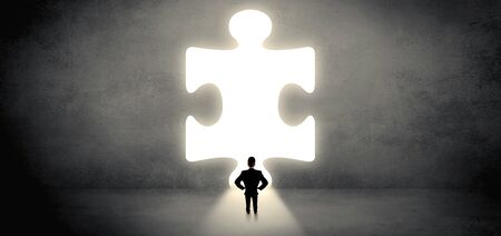 Businessman standing and looking to a big puzzle pieceの写真素材