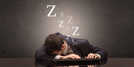Young businessman fell asleep at the table on his keyboard conceptの写真素材