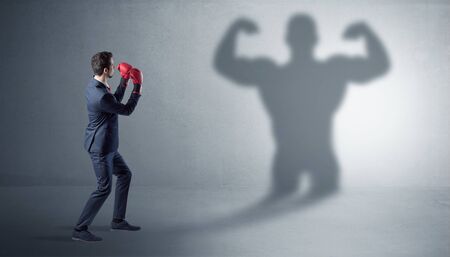 Businessman fighting with his bossy yelling shadowの写真素材