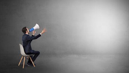 Businessman staying in an empty grey dark room with stuffs on his lapの写真素材