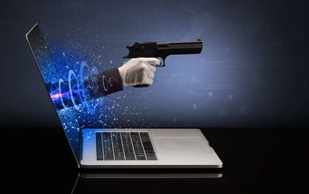 Hand with gun coming out of a laptop with sparkling effectsの写真素材