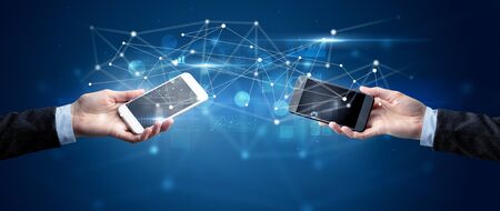 Close up of two hands holding smartphones and sharing business data