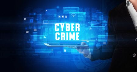 Young business person working on tablet and shows the digital sign: CYBER CRIMEの写真素材