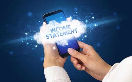 Female hand touching smartphone with INCOME STATEMENT inscription, cloud business conceptの写真素材