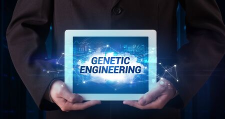 Young business person working on tablet and shows the inscription: GENETIC ENGINEERINGの写真素材