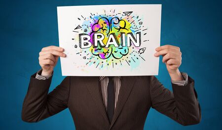 Young person holding white paper in front of her head with colorful brain concept