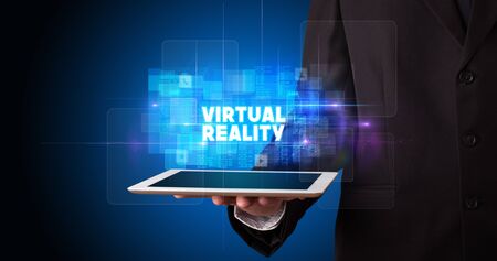 Young business person working on tablet and shows the inscription: VIRTUAL REALITYの写真素材